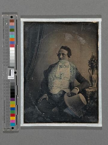 Portrait of a young man holding a large beaver-fur hat