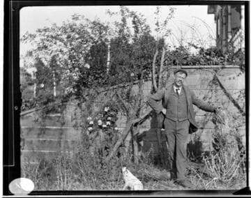 A man standing near a wall with a small dog