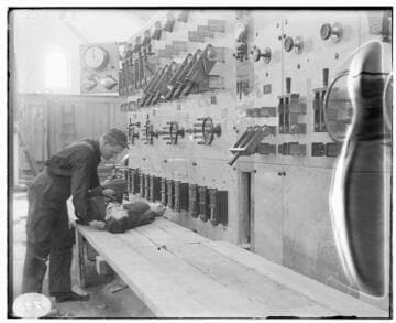 Two men conducting a first aid demonstration at the switchboard of Mill Creek #3 Hydro Plant