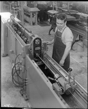 Machinist turning rifle barrel on lathe