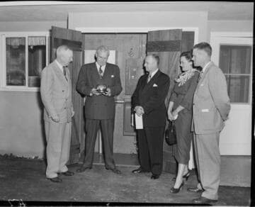 Three Edison men presenting  "one millionth" meter to owners in back yard of home