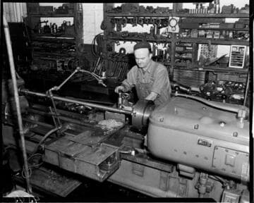 Machinist cutting threads on a long bar with a metal lathe