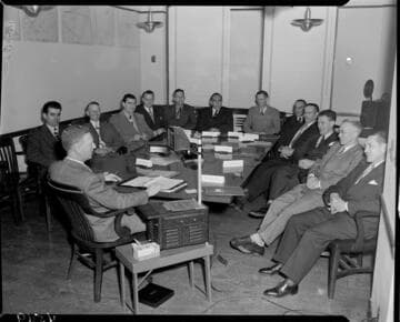 Men in suits at a meeting with  visual aids
