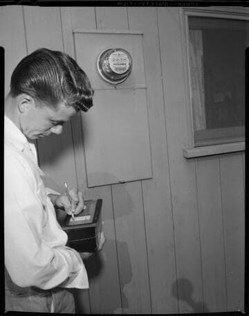 Meter reader recording data on computer data cards in customers backyard