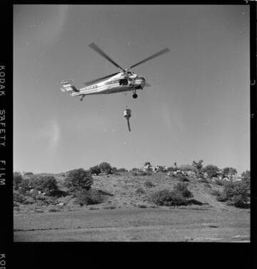 Sikorsky Helicopter airlifting concrete for tower footings from mixer trucks to tower sites