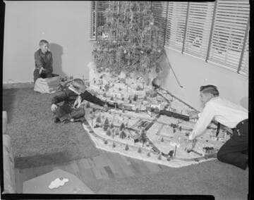 Family with model train layout around Christmas tree