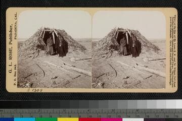 Two Navajo Indians standing in front of a hogan