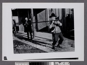 W. Parker Jr. owner of Lyon Pony Express Museum at Arcadia, Calif., helps his father carry the longest shotgun in the world from Museum Gun Room