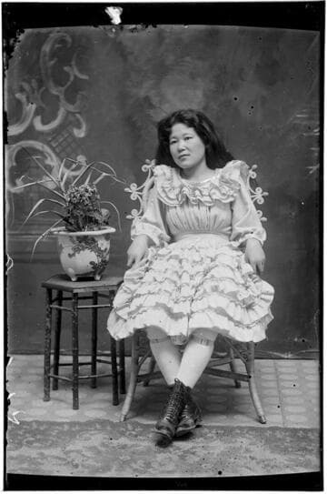 Portrait of a Chinese woman, seated, wearing dress with ruffles