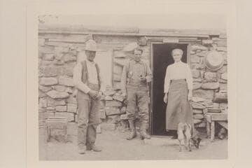 Stone cabin at the foot of the Vermillion Cliffs. Lee started construction of a stone cabin and this may have been completed later as shown. The man at left appears to be J. R. Bevard