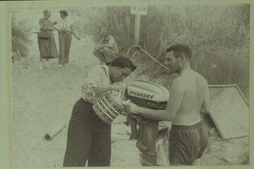 Lodell pours for Garth.  Margaret Marston discusses the situation with Dudy [sic] Thomas.  Dick Sprang sits in the background.  Preparation of boats for cruise of Grand Canyon, Lees Ferry