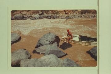 Nevills perched on the stern of a sadiron being lined at Vulcan Rapid