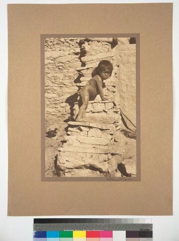 Hopi boy on stone steps of pueblo