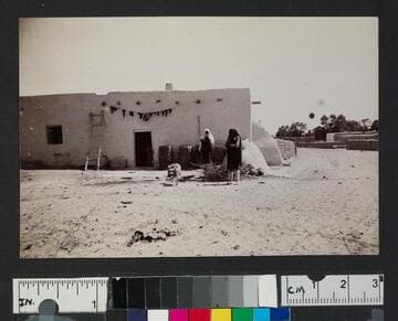 Pueblo Indian women in front of adobe building