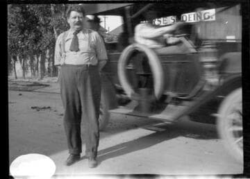 An unknown man standing in front of a moving car