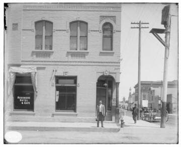 A man standing between the Rossmore Hotel & Cafe and the Santa Ana Local Office
