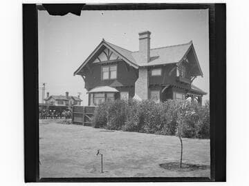 Unidentified two-story house with large lawn and new trees, back view