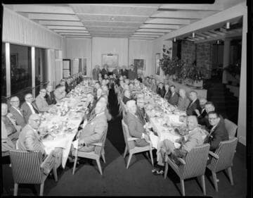 Men seated at two long tables for a banquet