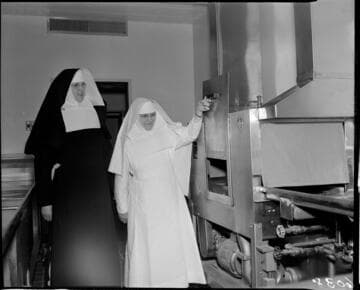 Two nuns looking at equipment in kitchen