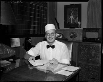 Man in a food service uniform seated at a desk