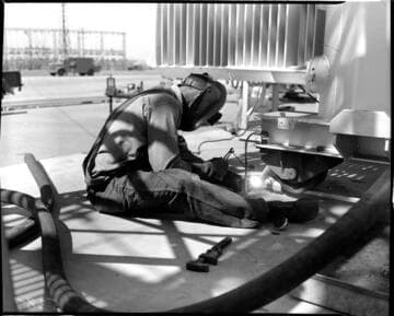 Man arc welding near base of transformers