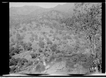 Long distance view of Kaweah #3 Power House on a hill with a tree in the foreground
