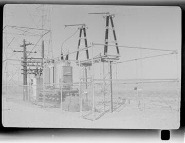 Small distribution substation near transmission tower in desert