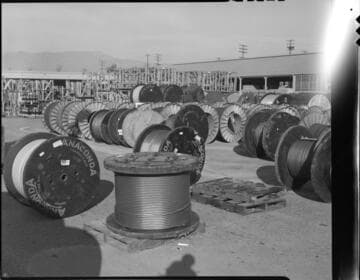 Group portrait with 5 men and a storage area with spools of Anaconda conductor with 2 variants
