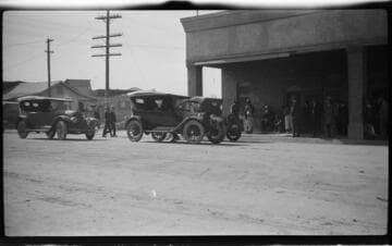 Group of people and automobiles at a building front