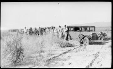 Several cars and men in the desert