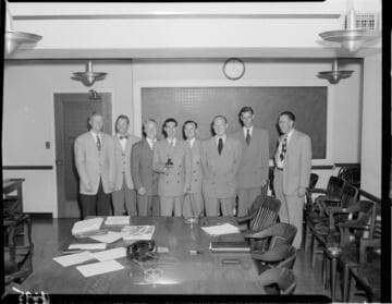 Group of 8 men with one holding an old light bulb