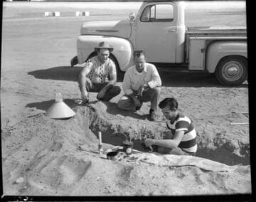 Three men installing airport runway light