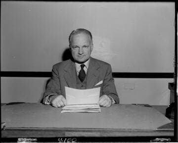 Man seated at desk reading printout