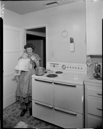 Woman heating formula while holding her baby