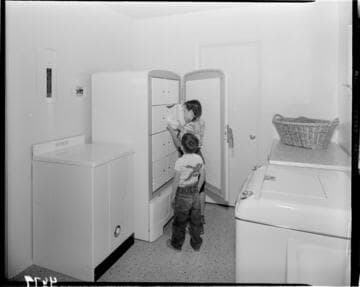 Children taking food out of upright freezer with 8 closed compartments inside
