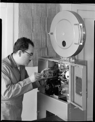 Man working with large theater size movie projector