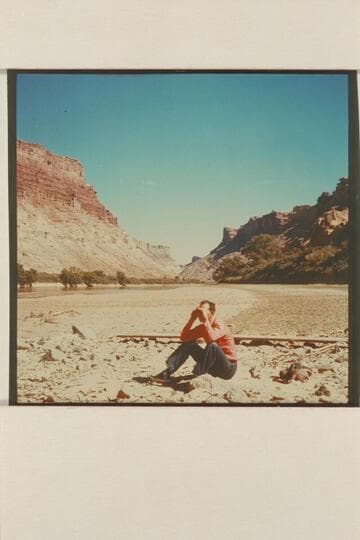 Kent Frost looking for trail sign in Cataract Canyon.  The greenery behind him is at mouth of side canyon opening into river at Mile 213.  Bank of river at left is at Spanish Bottom.  Compare with Nims photo #39