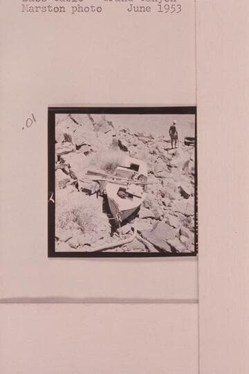 The Russell-Tadje boat "Ross Wheeler" on left bank above Bass Cable, Grand Canyon.  Mile 108.  Note the patches on the bow repairing the hole punched by a falling rock below Pipe Creek.  Claude Nichols is in background