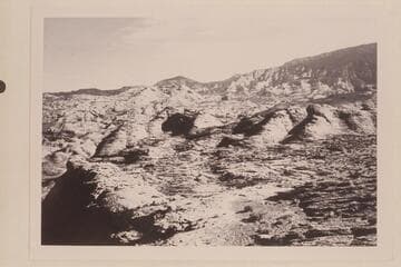 The basin of Nasja Creek from the point where the trail reaches the rim west of the mouth of the Creek. Cha Butte is below Navajo Begay. The basin of Bald Rock Creek is between Cha Butte and the sloping black top mesa at right.(Mesa 4903)