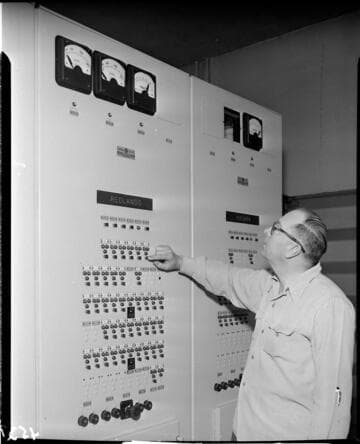 Man pushing relay button on switchgear panel for Redlands and Yucaipa